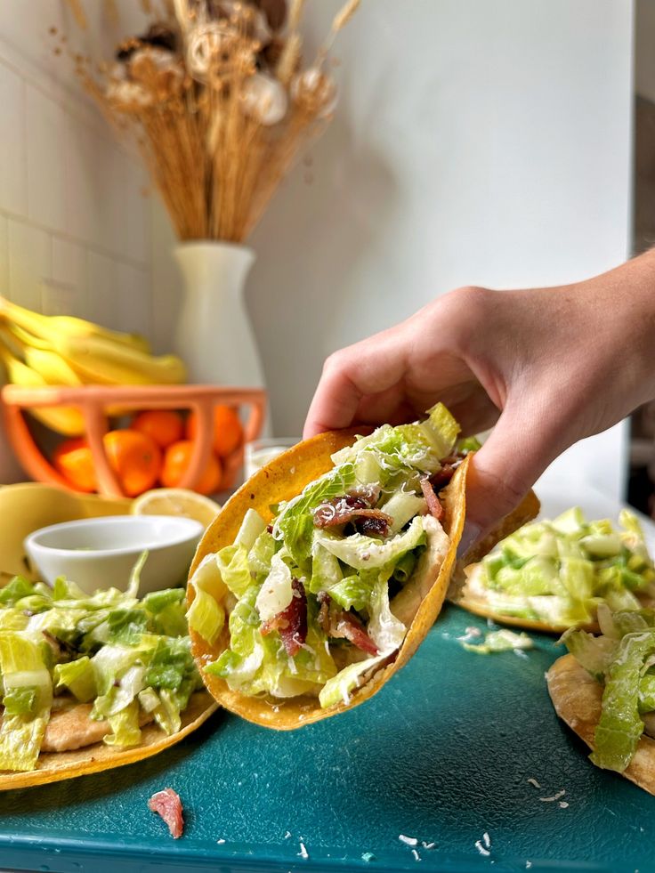 a person holding a tortilla filled with lettuce and other food items