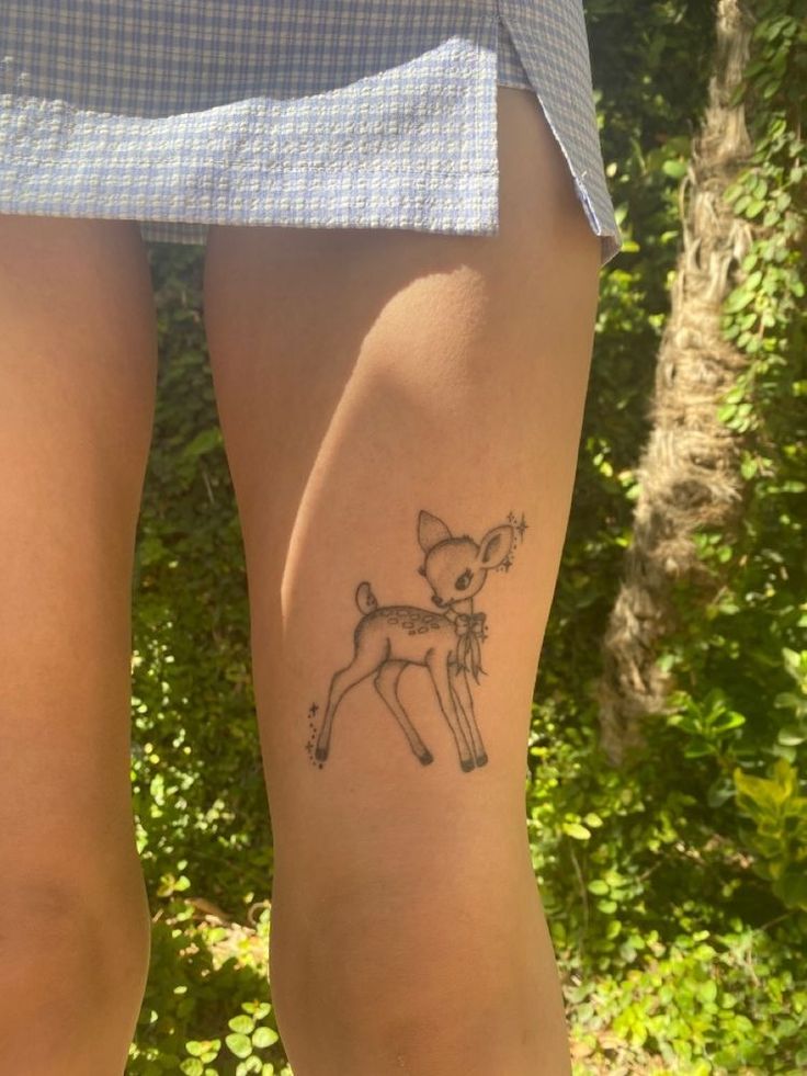 a woman's legs with a small deer tattoo on them