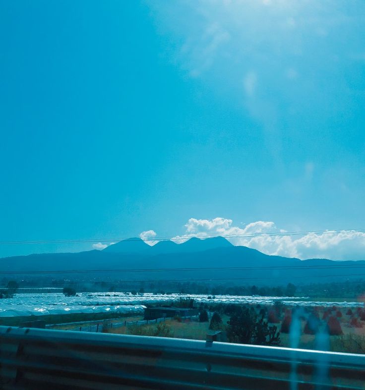 the sun is shining brightly over mountains in the distance as seen from a moving vehicle