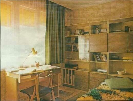 an old photo of a bedroom with a desk and bookcases in the corner