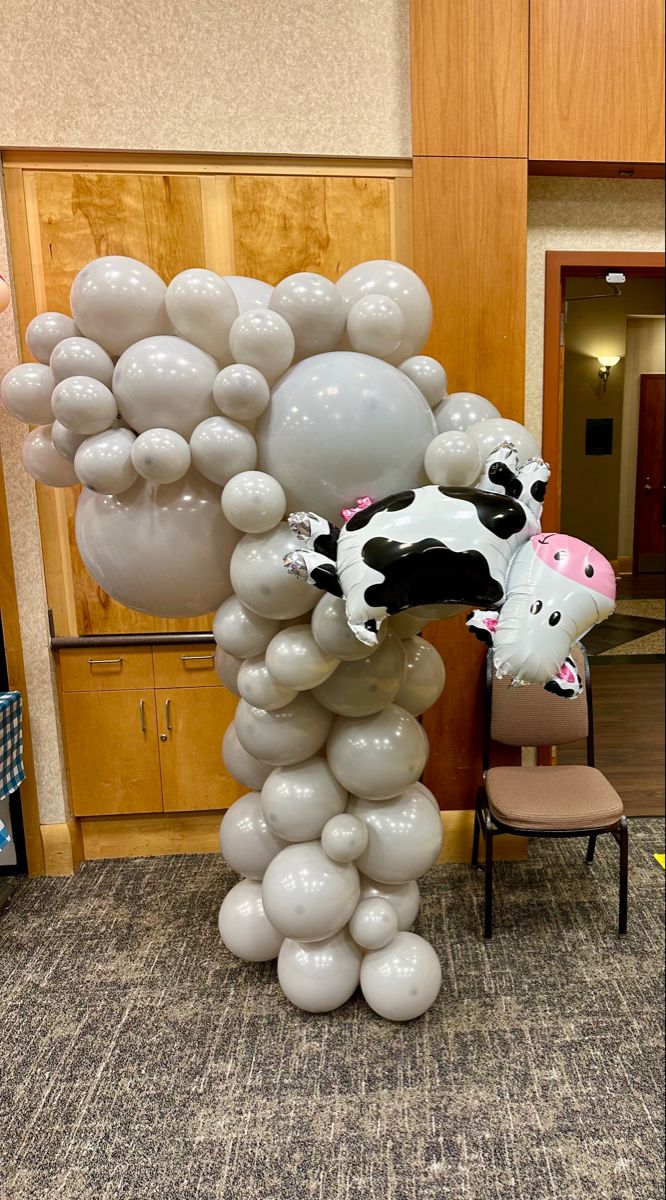 there is a cow balloon sculpture in the middle of an office lobby with chairs around it