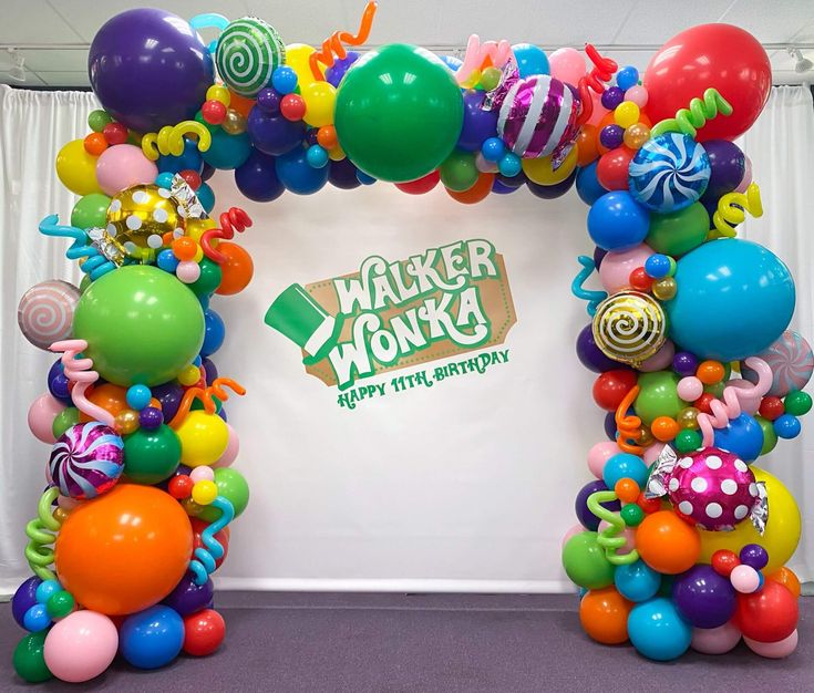 an arch made out of balloons and streamers with the words walker wonka on it