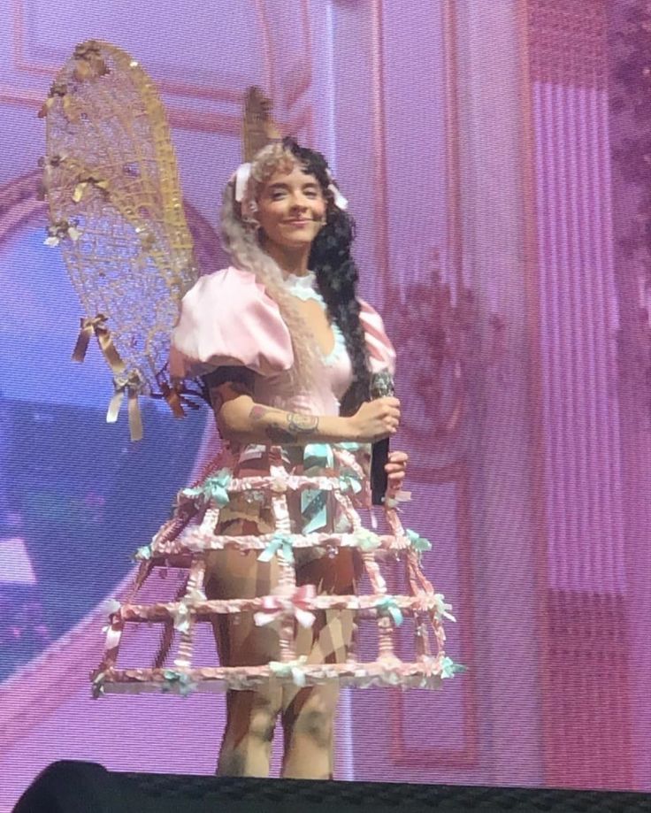 a woman in a pink dress holding a tennis racquet on top of a stage