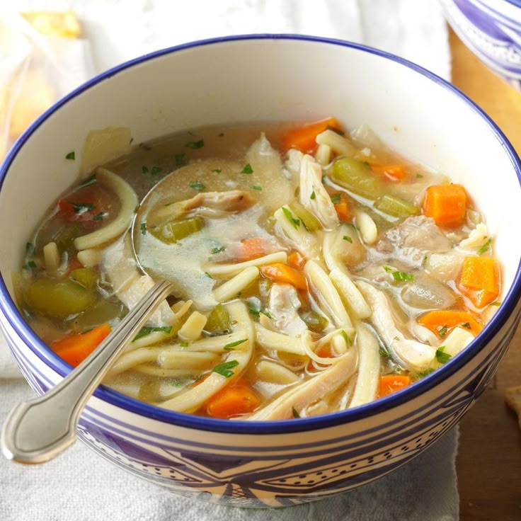 a bowl of soup with noodles, carrots and celery