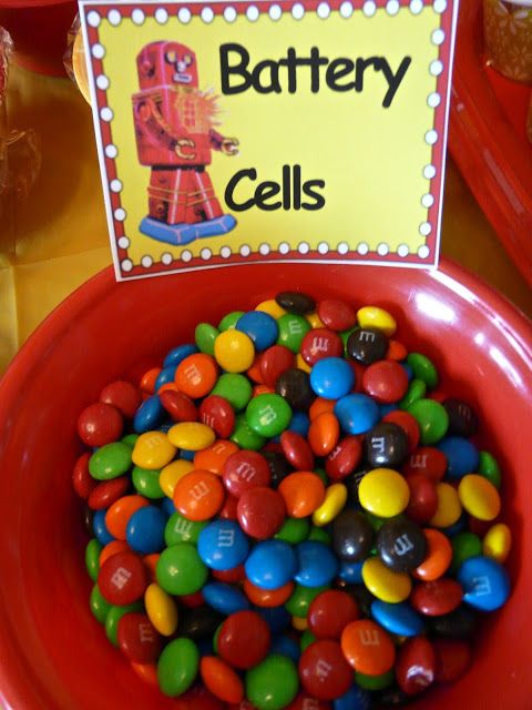 a red bowl filled with lots of candy next to a sign that says battery cells