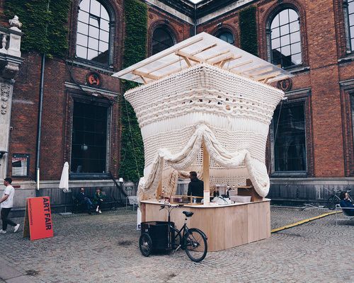 a white bed sitting in the middle of a courtyard next to a building with lots of windows