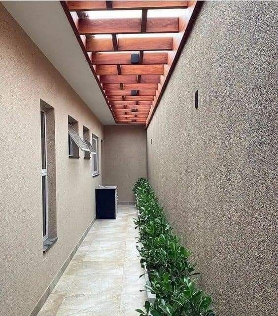 an empty hallway between two buildings with plants on either side