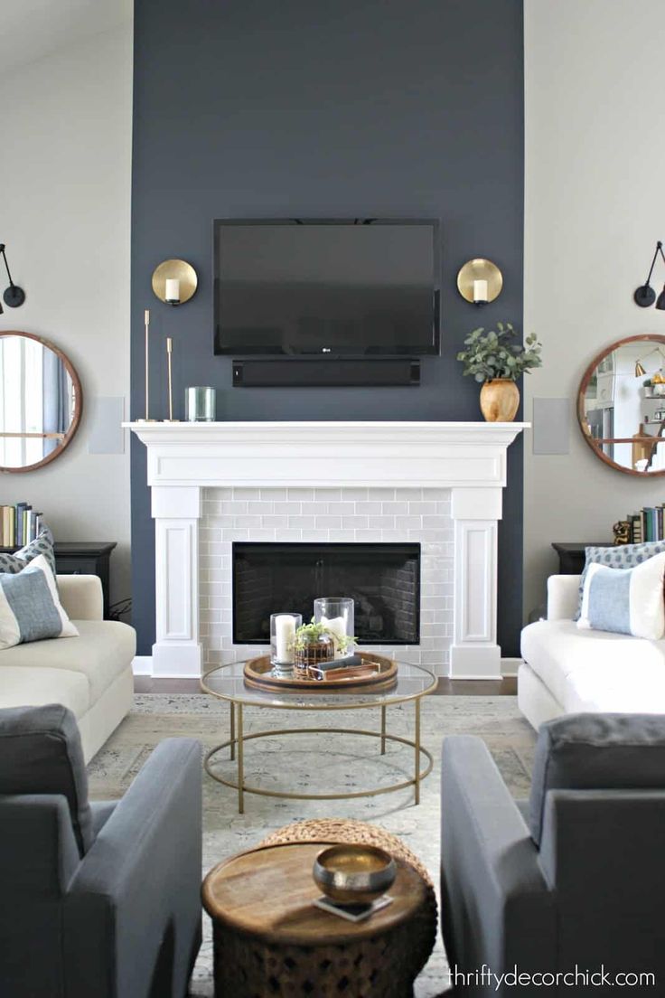 a living room with two couches and a tv on the wall in front of a fireplace