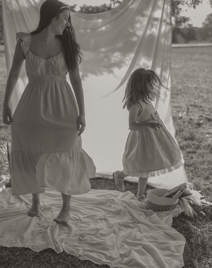 two women in dresses are standing near a tent