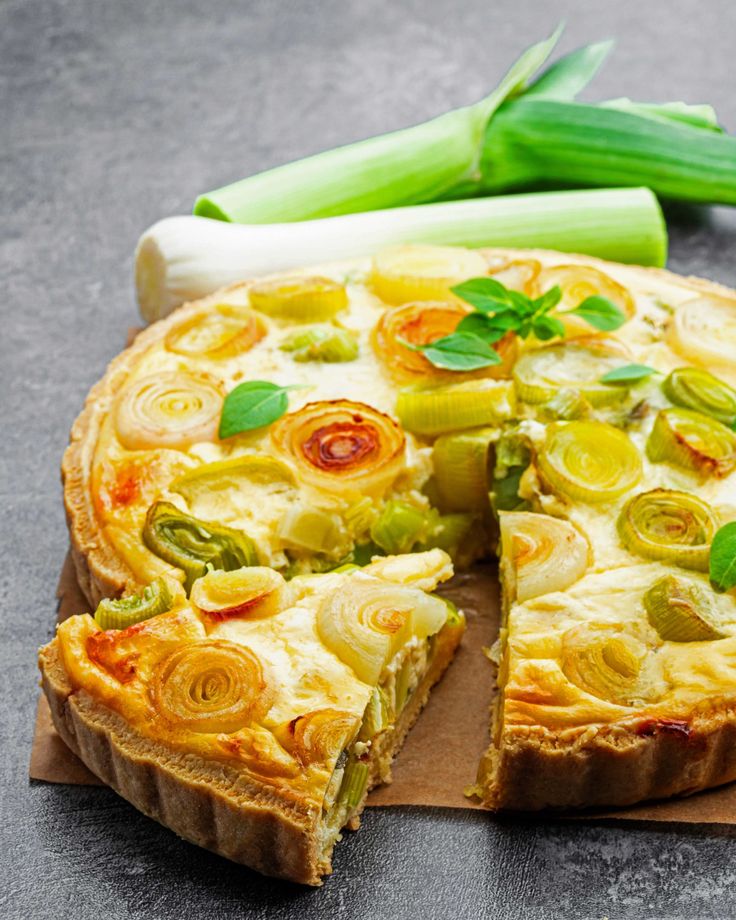 a vegetable quiche on a cutting board next to celery