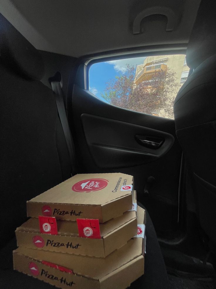 three pizza boxes stacked on top of each other in the back seat of a car