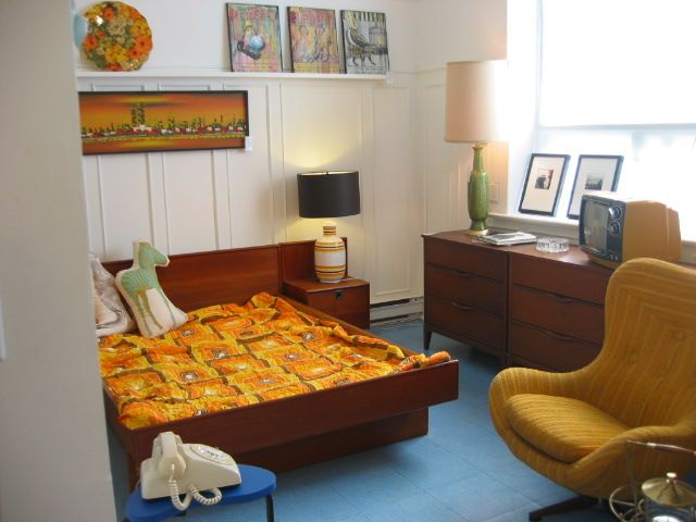 a bed room with a neatly made bed next to a dresser and chair in it