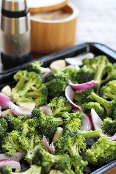 broccoli florets and onions are in a baking pan on the table