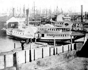 an old black and white photo of boats docked at a pier in the harbor with other ships