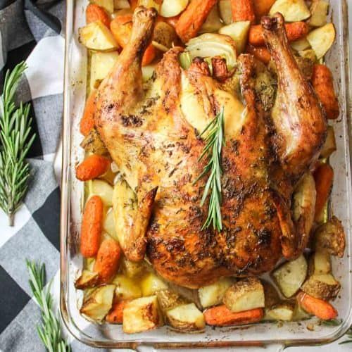 chicken, potatoes and carrots in a casserole dish on a checkered table cloth