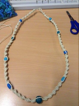 a necklace with blue beads is sitting on a table next to a pair of scissors