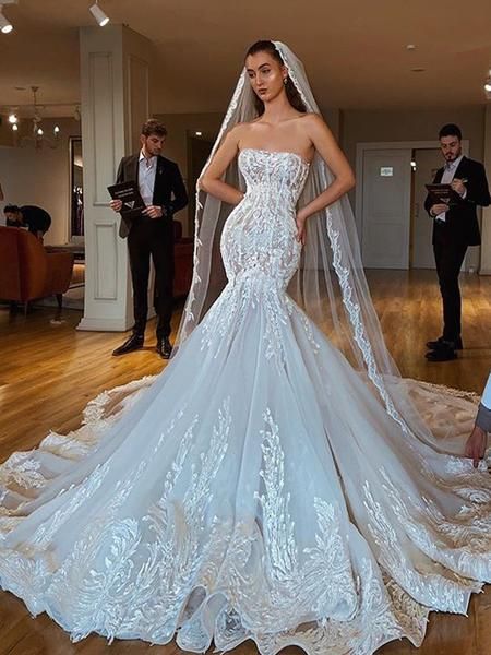 a woman in a wedding dress standing on a wooden floor