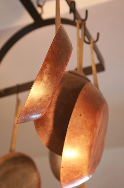 copper pots and pans are hanging from the ceiling