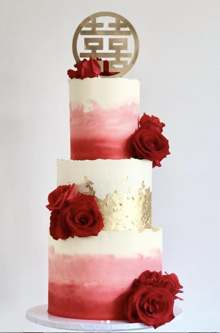 a three tiered cake with red flowers on top