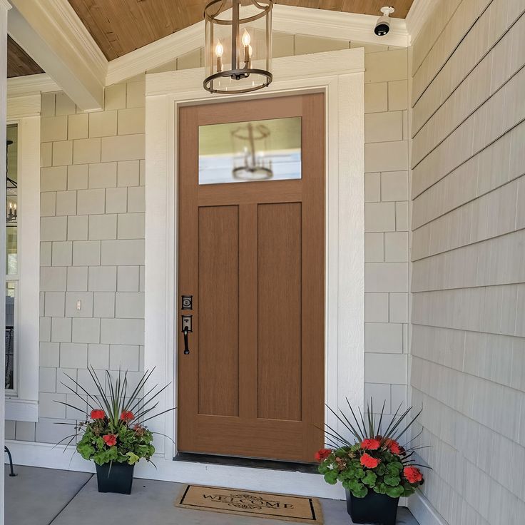 a front door with two planters on the side and a light fixture above it