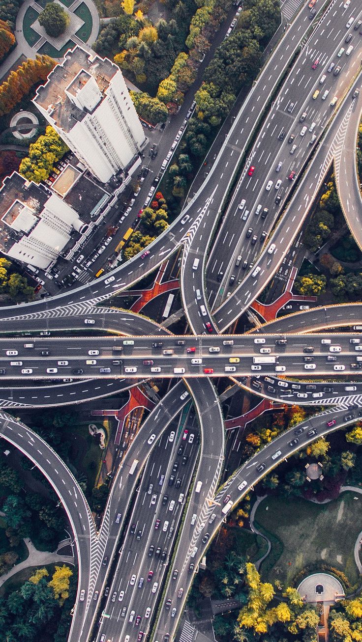 an aerial view of multiple roads in the middle of a city with trees and buildings