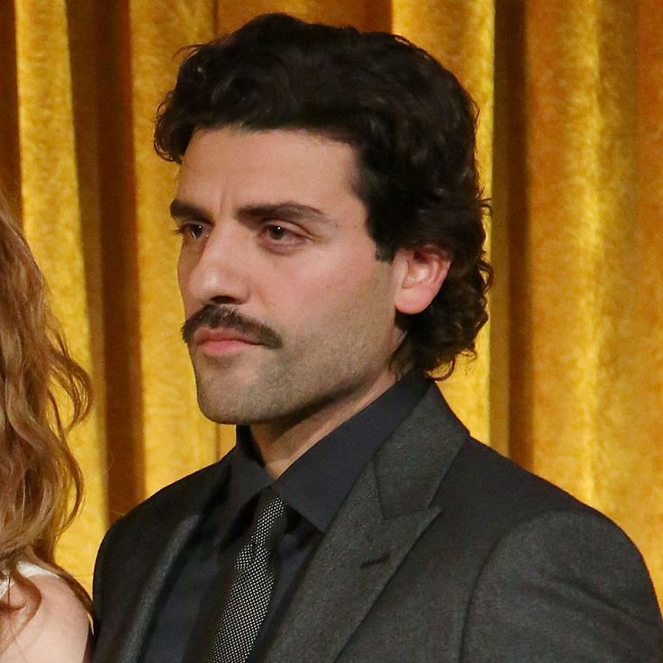 a man and woman standing next to each other in front of yellow curtained curtains