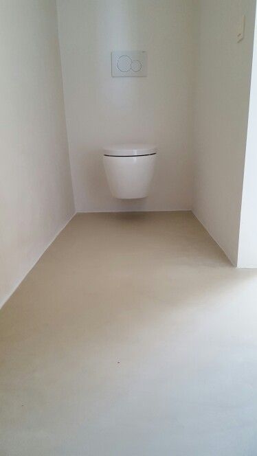 an empty bathroom with a toilet in the corner and light coming from the window on the wall