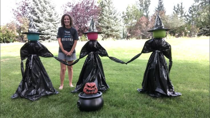 a woman standing in the grass with three witches holding hands and wearing black plastic bags