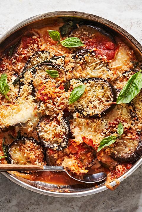 a pan filled with pasta and eggplant covered in sauce, parmesan cheese and basil leaves