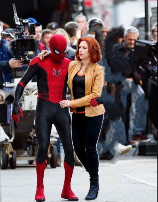 spider - man and woman walking down the street in front of cameramen on set