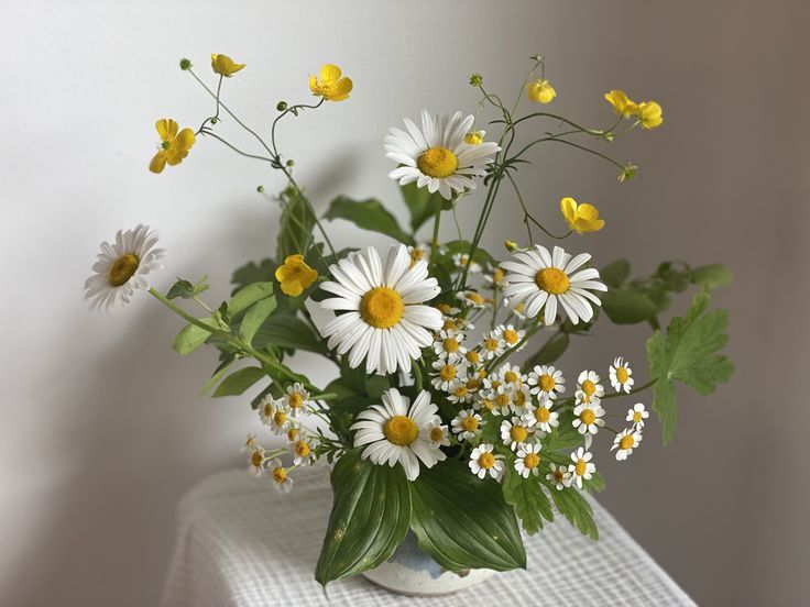 a vase filled with lots of white and yellow flowers