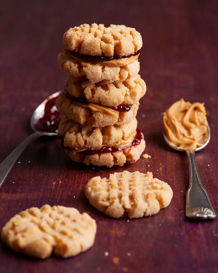 peanut butter and jelly cookies stacked on top of each other with spoons next to them