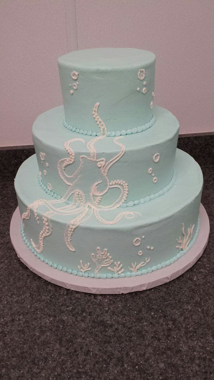 a three tiered blue cake with white decorations