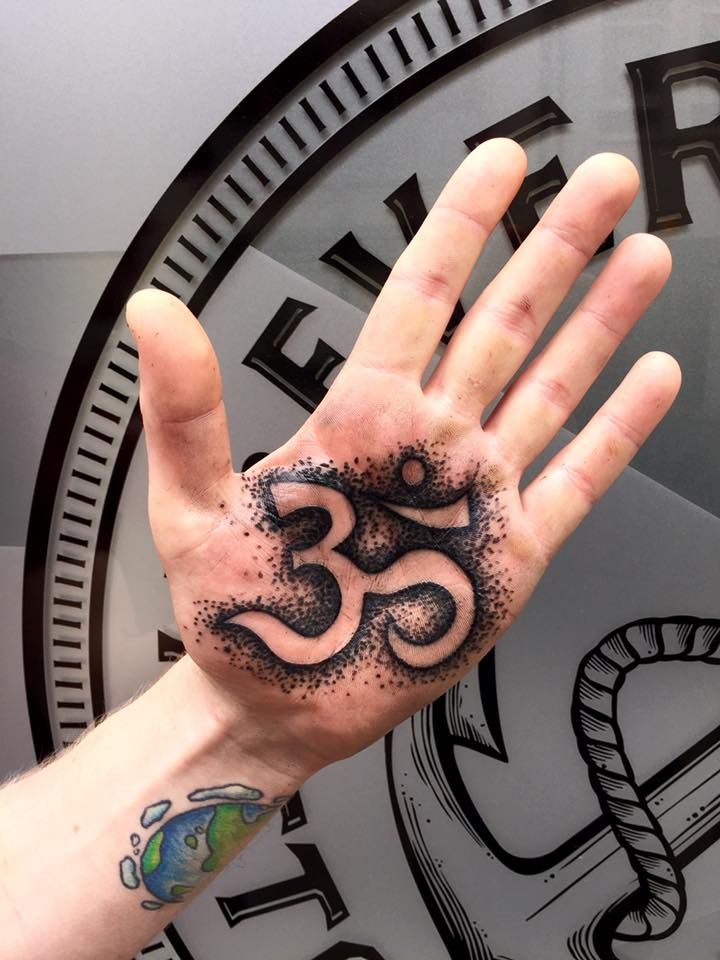 a person's hand with a tattoo on it and an om sign in the middle