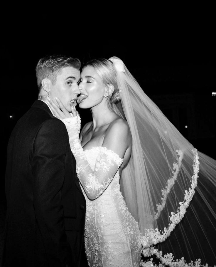 a bride and groom kissing in front of a black background at their wedding reception,