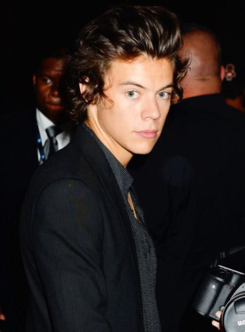 a young man in a suit and tie looking at the camera while standing next to other people