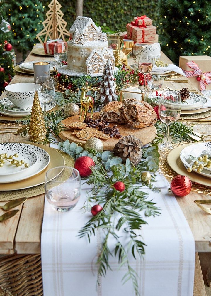 a table set for christmas dinner with plates, silverware and other holiday foods on it