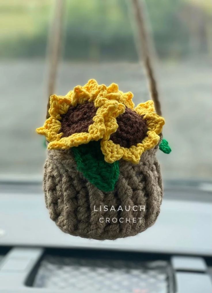 a crocheted sunflower hanging from a car dashboard