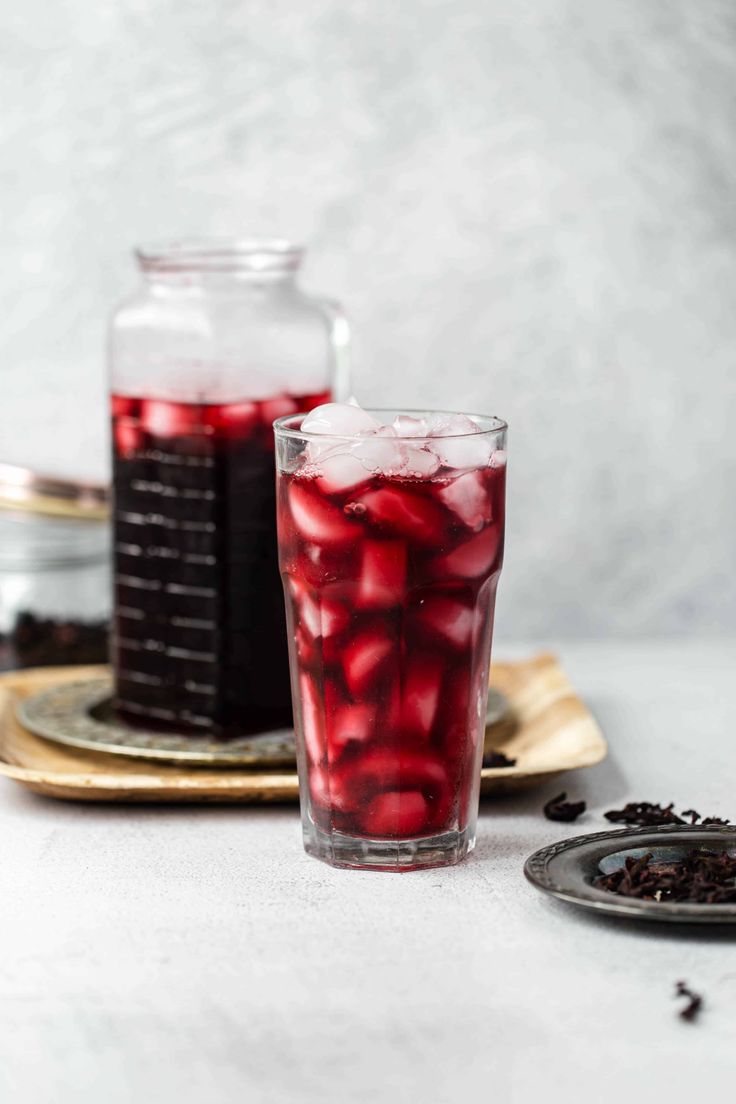 a glass filled with liquid sitting on top of a table next to a plate full of food