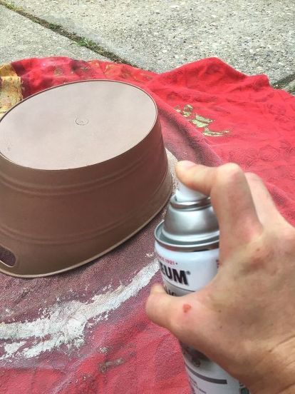 a person is spray painting a cake with chocolate icing on a red blanket outside