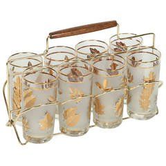 a set of six glass cups with gold leaves on the rim and a wooden handle