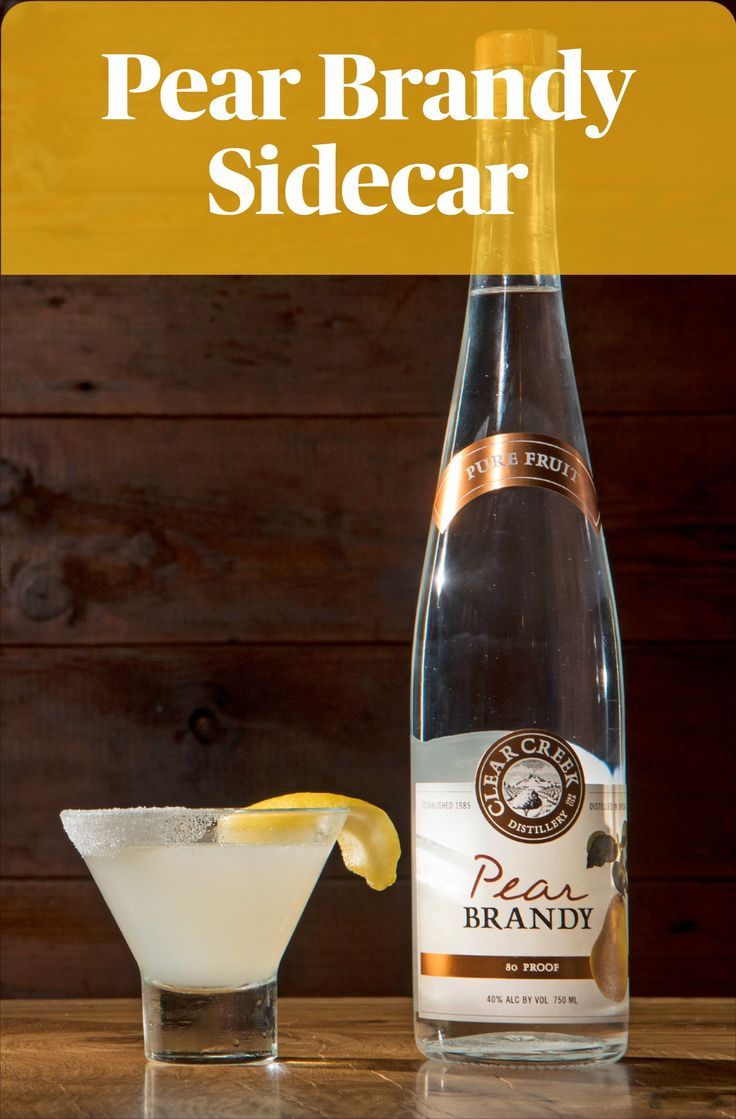 a bottle of pear brandy sidecar next to a martini glass with a lemon wedge