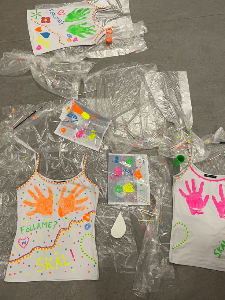 plastic bags filled with handprints and t - shirts on top of a floor