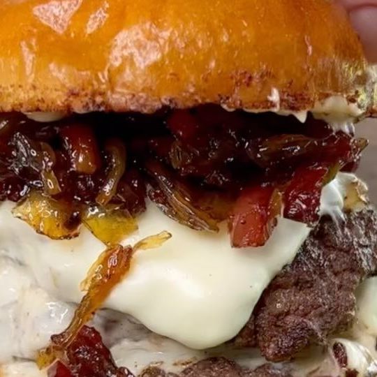 a close up of a burger with meat and cheese