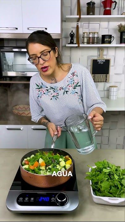 a woman pouring water into a bowl filled with vegetables