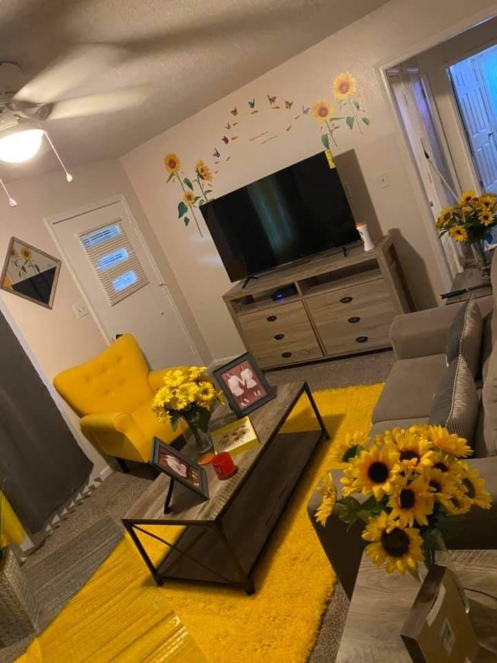 a living room filled with furniture and yellow flowers