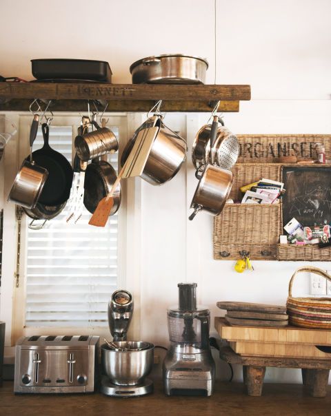 a kitchen with pots and pans hanging on the wall next to a shelf filled with utensils