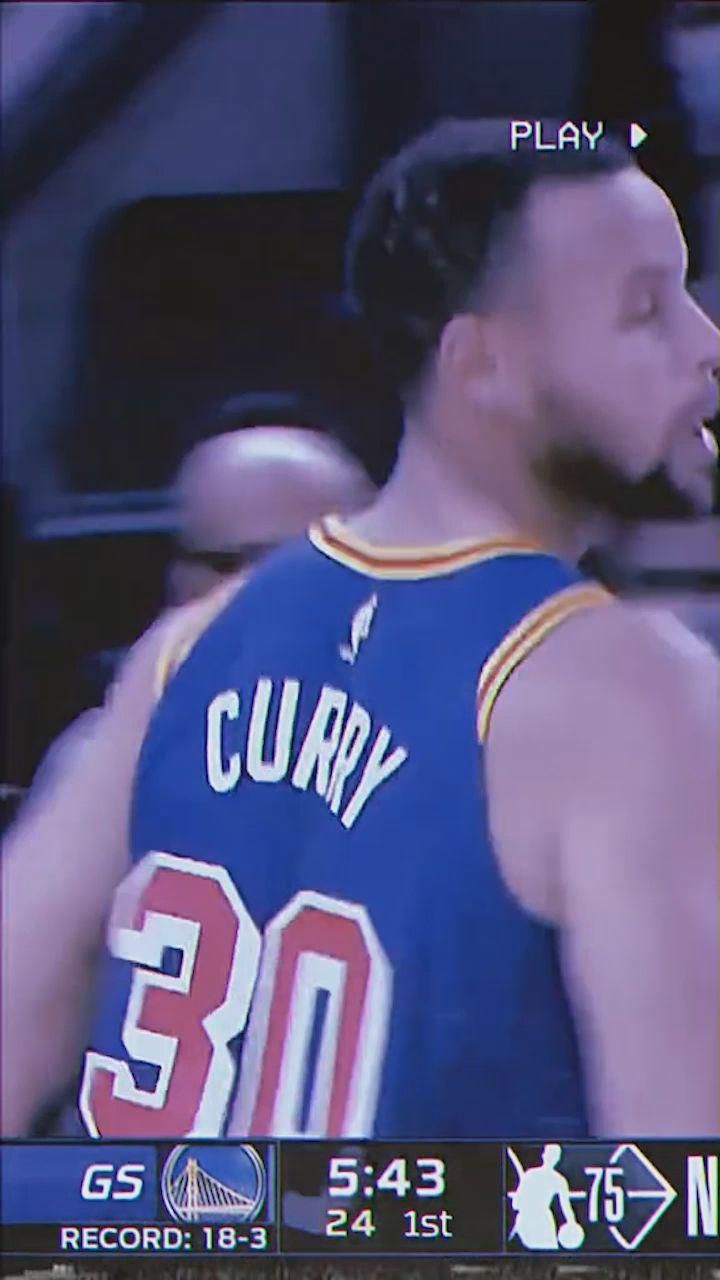 a man in a blue jersey is on the television screen and has his hand up to his mouth