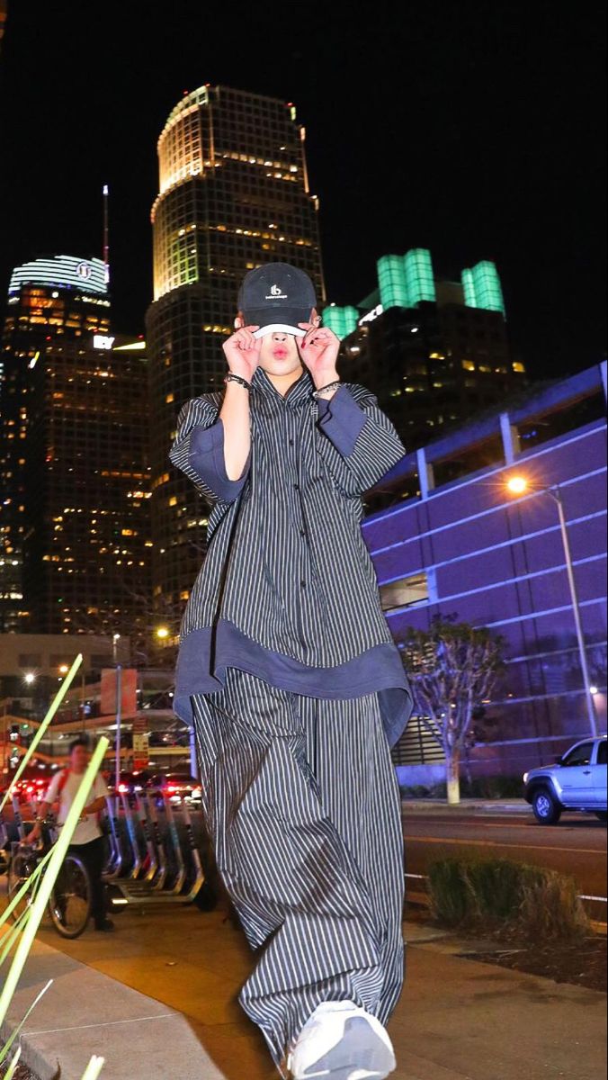 a man standing in front of a tall building at night with his hands on his face