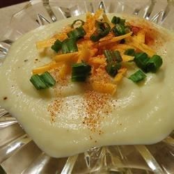 a glass plate topped with mashed potatoes covered in gravy and chopped green onions